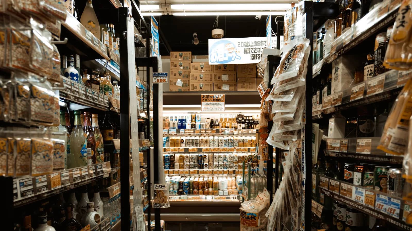 日本商店的貨架走道,兩側陳列乾貨零食、瓶裝酒類與包裝食品