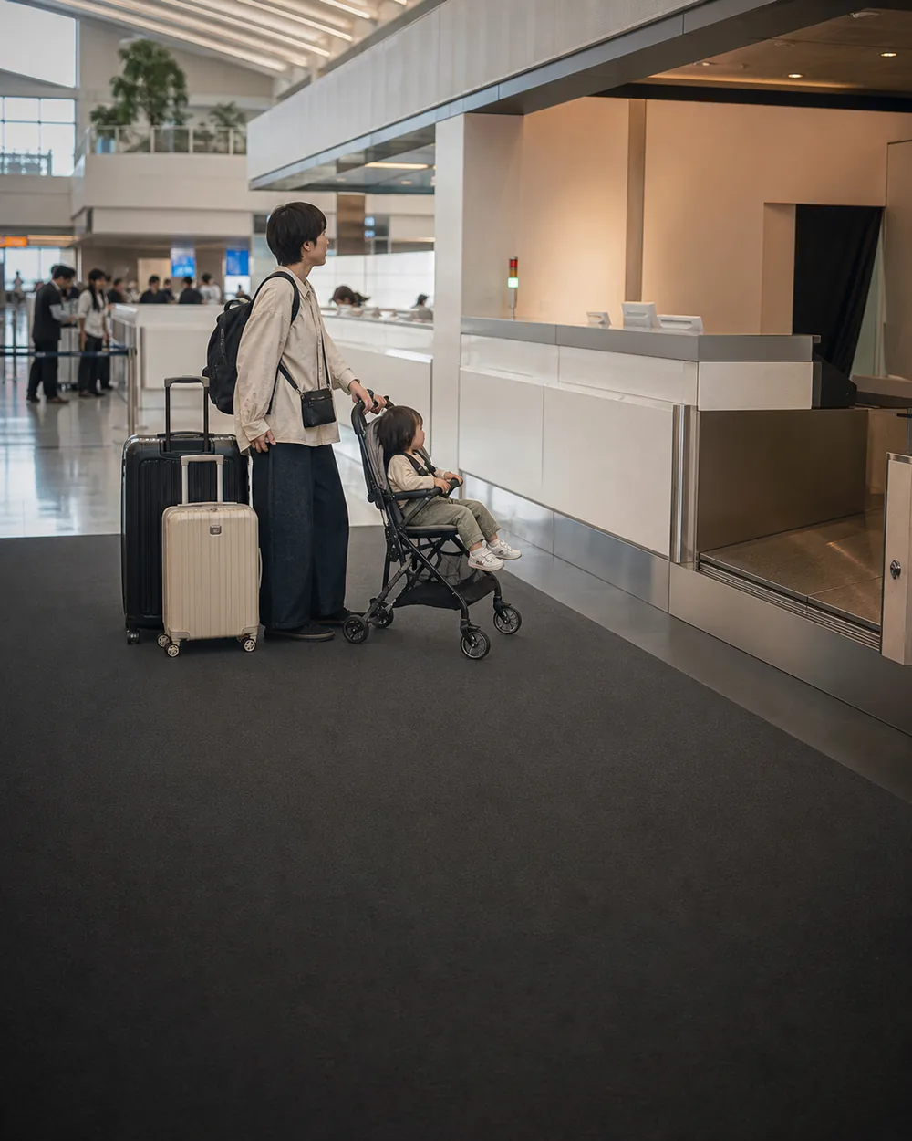 親子家庭在那霸機場到達大廳旁的行李服務櫃位前,身旁有推車與行李箱
